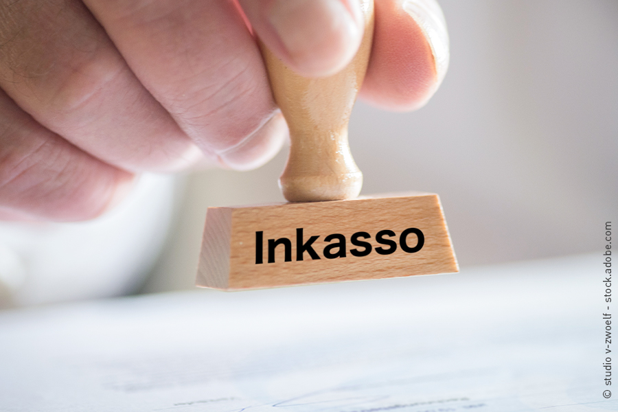 Eine Hand hält einen Stempel mit der Aufschrift Inkasso