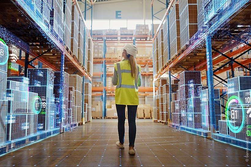 eine-frau-mit-warnweste-läuft-durch-ein-digitalisiertes-lager (1)