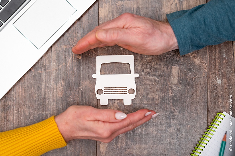 frau-und-mann-halten-hände-schützend-über-lkw-symbol